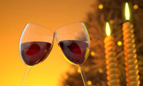 Two wine glasses touching with candles lit in the background